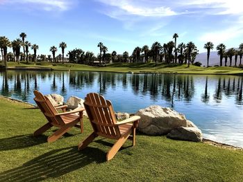 Chairs by lake against sky