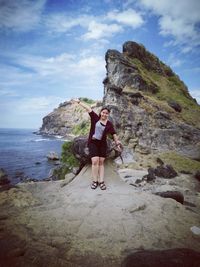 Full length of woman standing on rock formation at beach