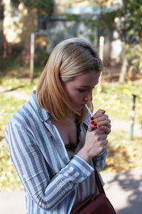 Woman igniting cigarette while standing at park