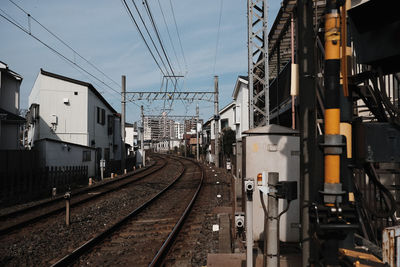 Railroad tracks in city against sky