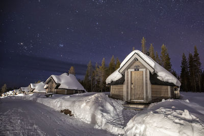 Snow covered houses by building against sky at night