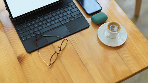 High angle view of laptop with coffee cup in table