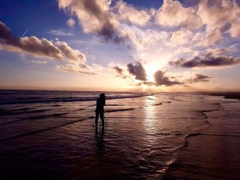 Silhouette man on beach against sky during sunset