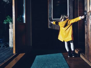 Rear view of woman standing against yellow door