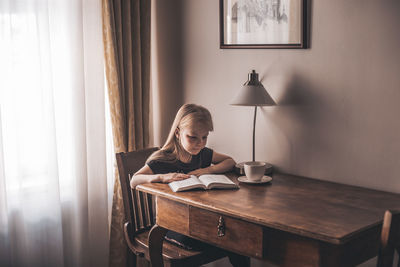 Girl reading book at table