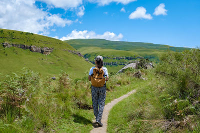 Rear view of woman walking on mountain against sky