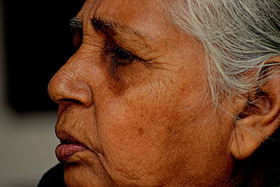 Close-up of woman wearing mask against black background