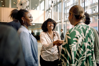 Smiling female entrepreneur shaking hands with delegates during seminar at convention center