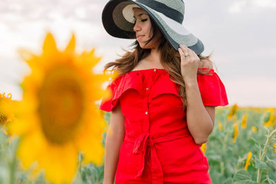 Full length of beautiful woman standing by red flowering plants