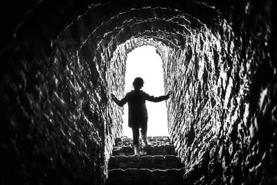 Rear view of silhouette boy standing in tunnel