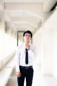 Portrait of young man standing against wall