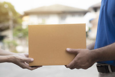 Midsection of man holding paper against wall