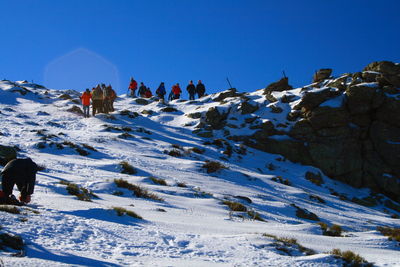 Low angle view of people on snow covered mountain against sky