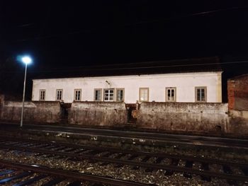 Illuminated railroad tracks by building at night