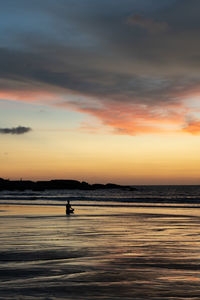 Silhouette person on beach against sky during sunset