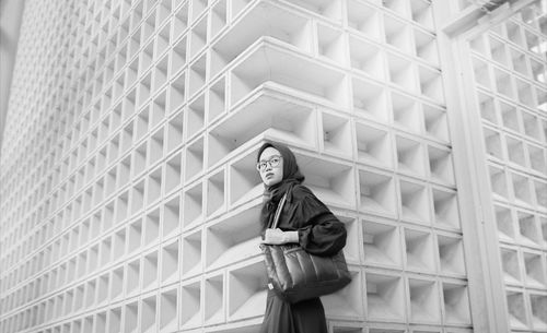 Low angle view of woman standing against modern buildings