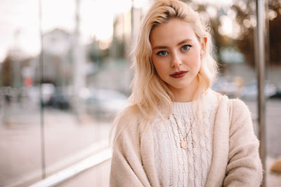 Portrait of young confident woman standing on bus stop in city