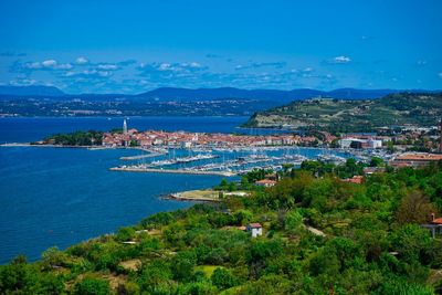 High angle view of city by sea against blue sky