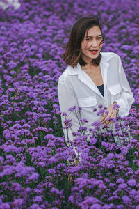 Portrait of beautiful woman standing amidst purple flowering plants