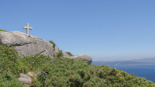 Cross on mountain against clear blue sky