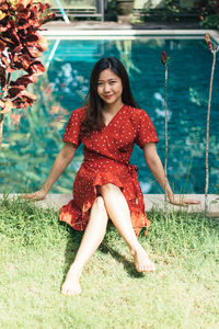 Portrait of woman sitting on land against swimming pool