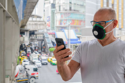 Man holding mobile phone while standing on bus