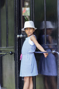 Portrait of cute girl standing against glass