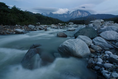 Rocks in river against sky