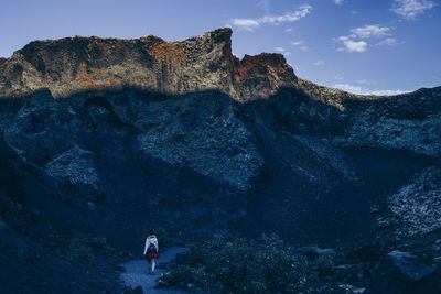 Low angle view of person on rock against sky