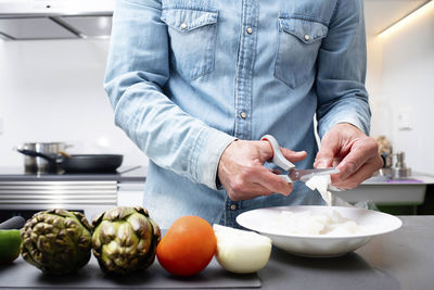 Midsection of man preparing food in kitchen at home