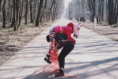 Man carrying woman in costume on road against bare trees