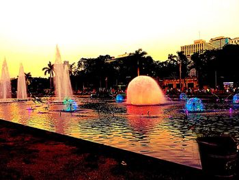 Illuminated built structures against clear sky at sunset