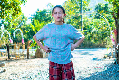 Portrait of young woman standing against trees