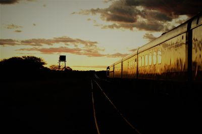Silhouette of railroad tracks against sunset sky