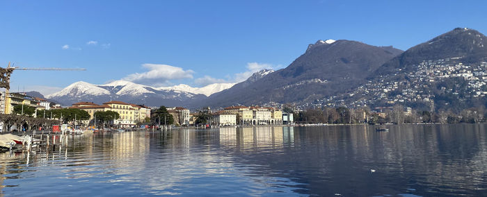 View of buildings by lake against sky