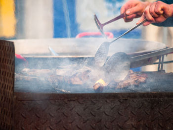 Midsection of person preparing food on barbecue grill