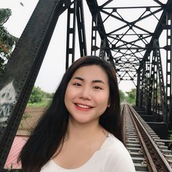 Portrait of smiling young woman on railroad tracks