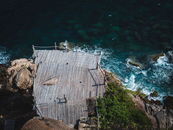 Scenic high angle view of wood deck platform on rocky coastline with wave. koh tao island, thailand.