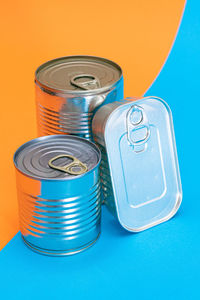 A group of stacked tin cans with blank edges on split blue and orange background