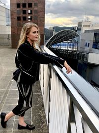 Full length of woman standing on railing in city