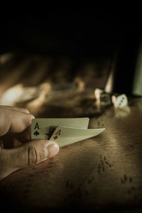 Close-up of hand holding paper with text on table