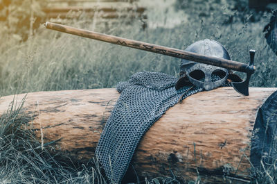 Metal chain mail, helmet and ax lie on wooden log. viking armor. historical film concept.