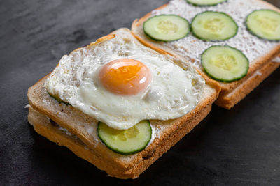 Close-up of two fresh crispy sandwich of toasted bread, fried eggs, cucumber, meat, cheese 