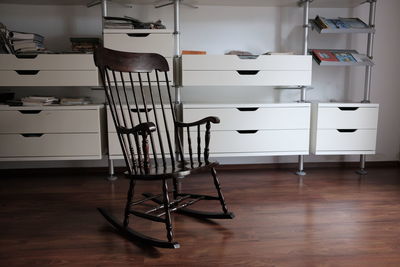 Rocking chair on hardwood floor against shelves at home