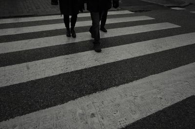 Low section of people walking on zebra crossing