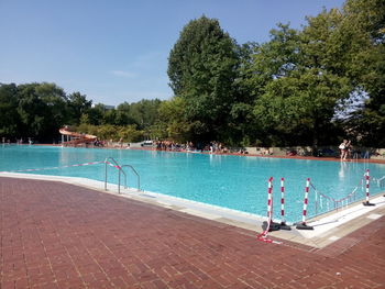 Swimming pool by trees against sky