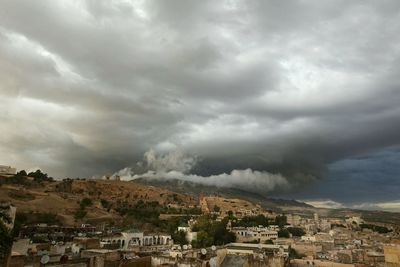 Buildings in town against cloudy sky