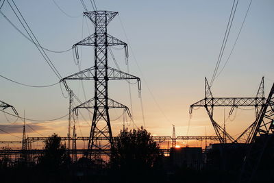 Low angle view silhouette of electricity pylon against sky during sunset