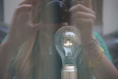 Close-up of woman photographing light bulb