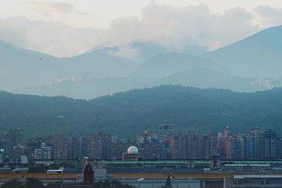 Buildings in city against cloudy sky